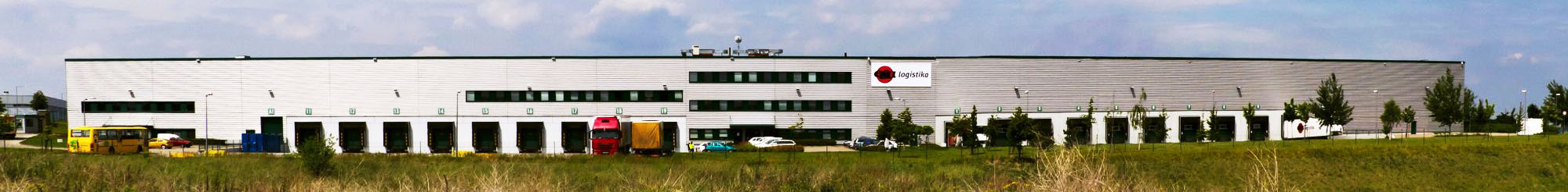 Skladování - budova chlazeného a distribučního skladu v Jažlovicích, přední pohled, logo ESA logistika, rampy, parkoviště, kamiony, zeleň